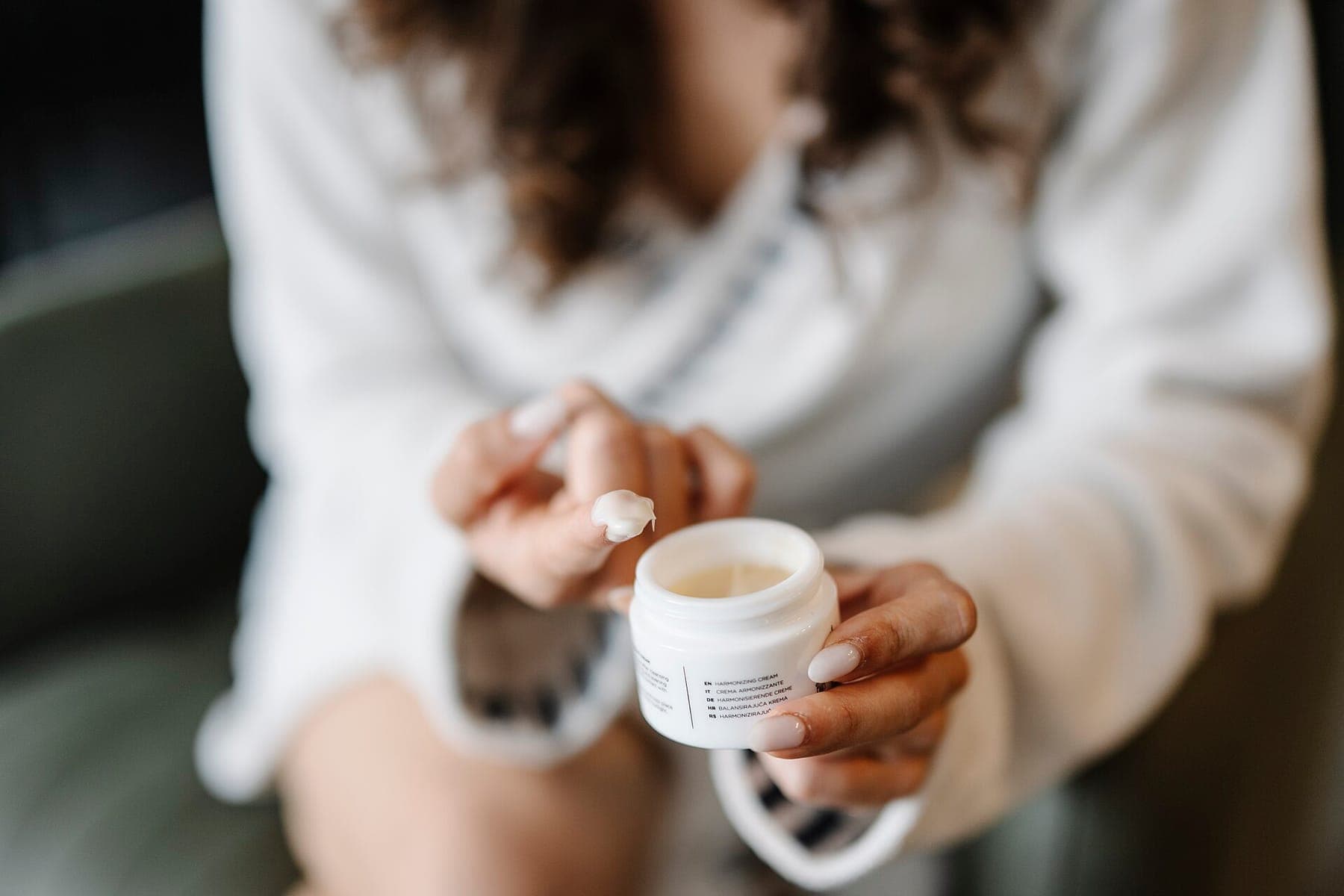 Person applies cream for skin from a jar closeup